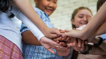 Group of elementary students holding hands in cooperation