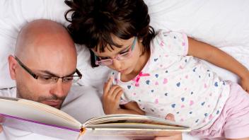 Dad reading picture book with first grade daughter