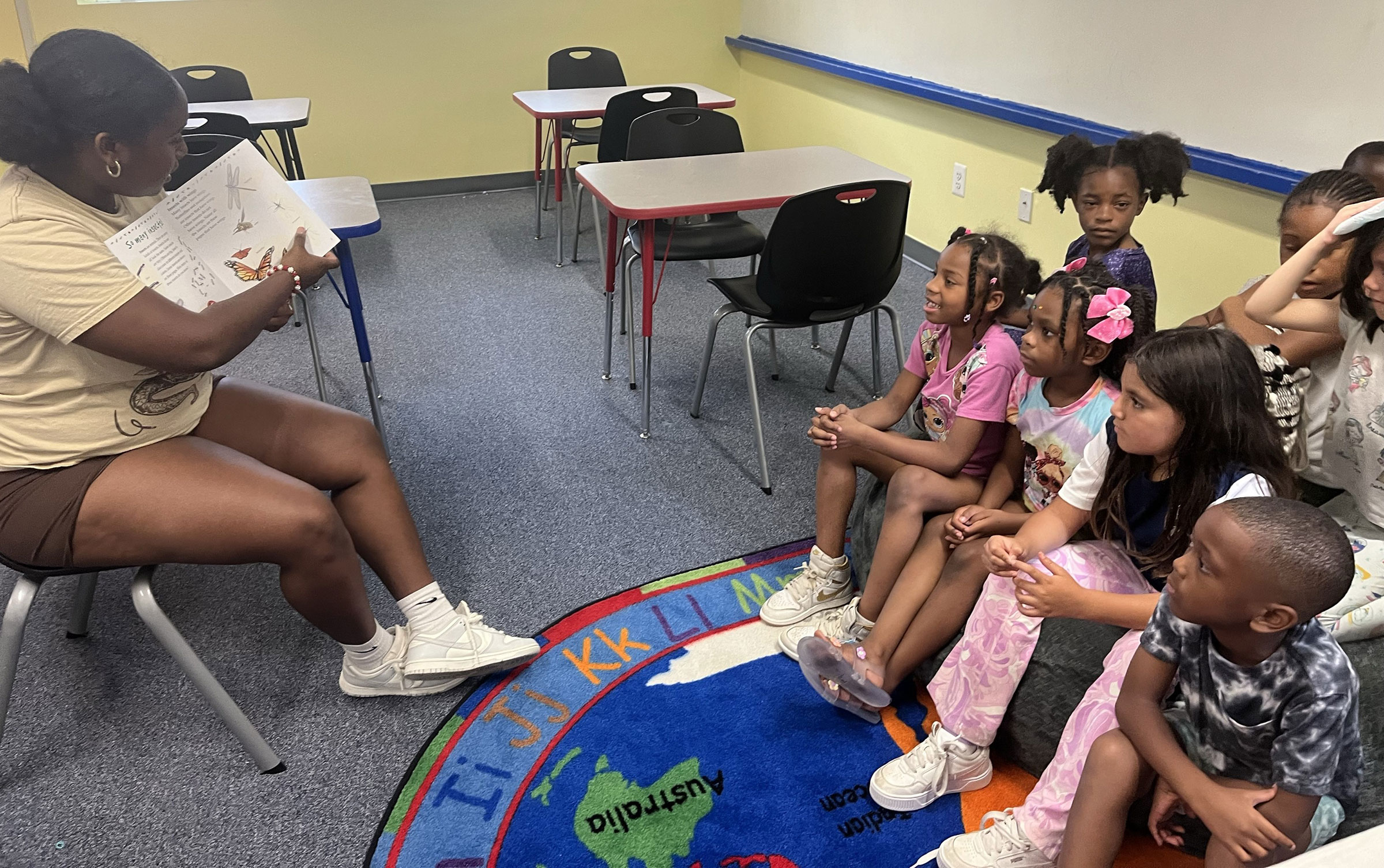 Summer program leader reading picture book to group of young kis