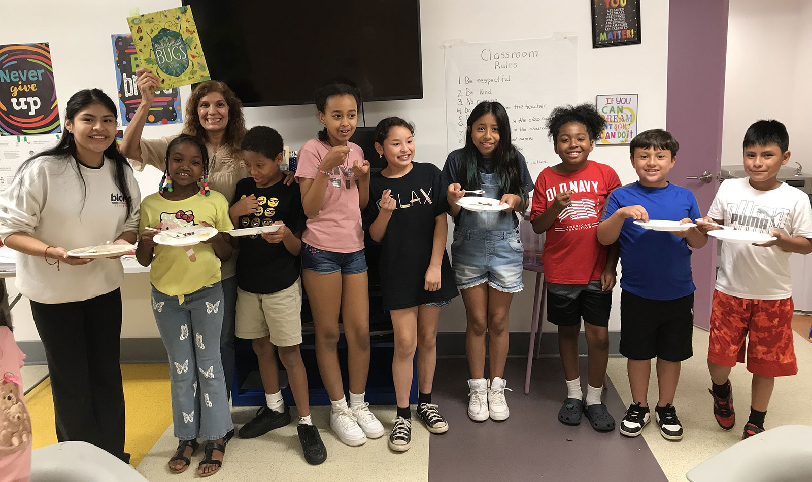 Group of young kids and teachers holding plates of food from bugs