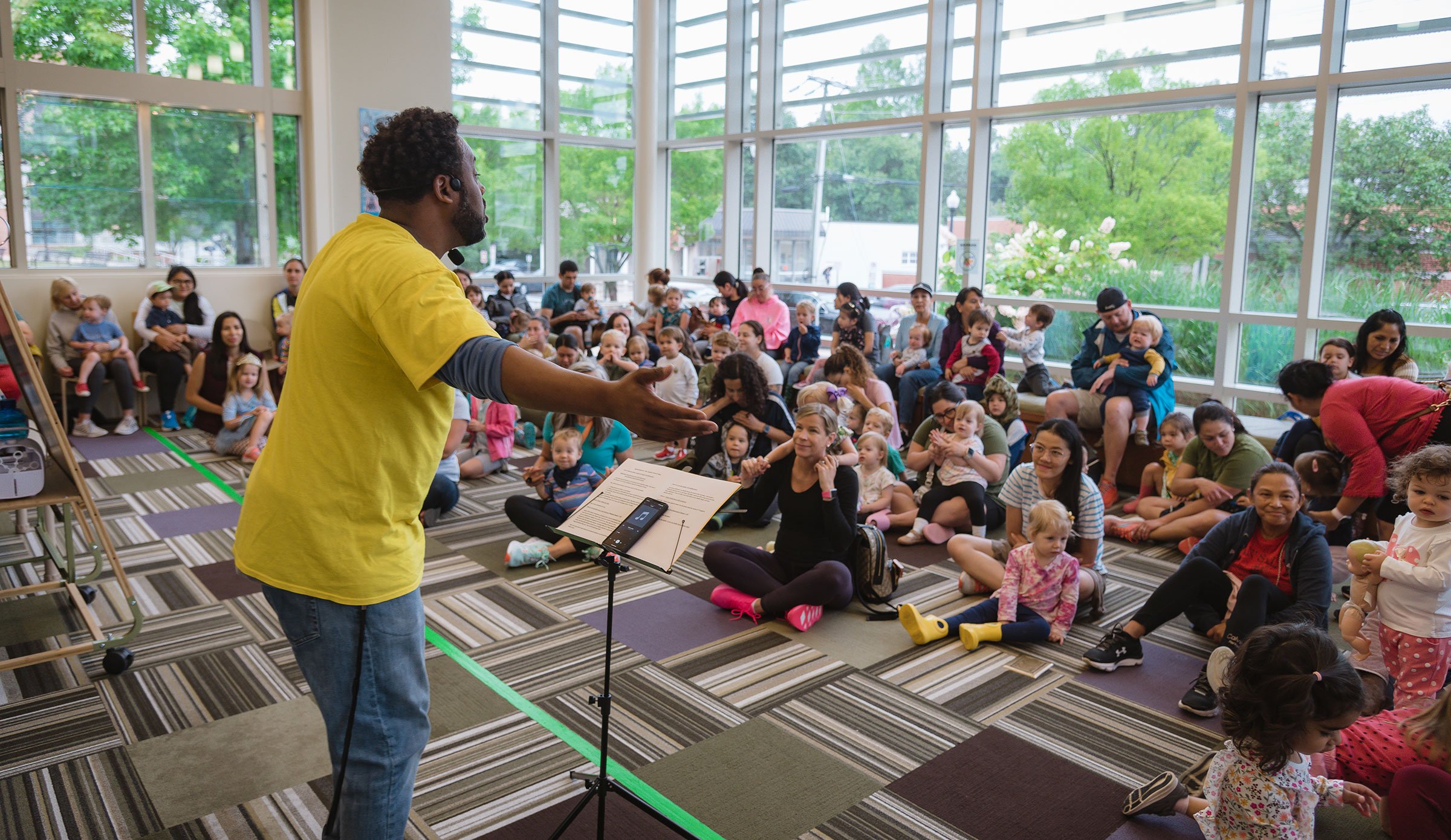 Public librarian leading a read aloud for large group of kids