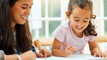 Mother helping preschool daughter with simple writing activity