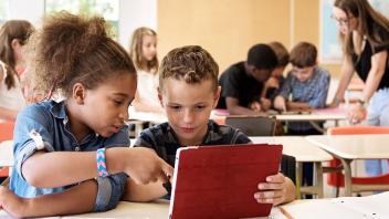 two elementary students working on tablet together in class