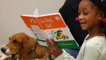 Young girl smiling while reading Go Dog Go