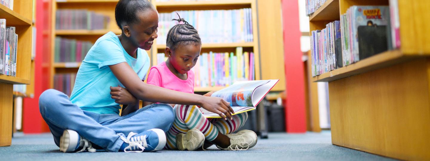 Two young girls looking at picture books at the library