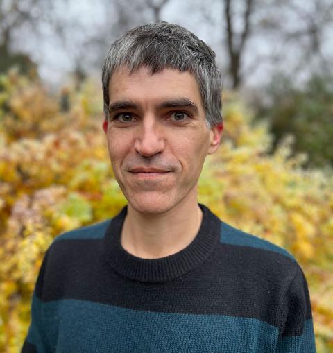 Outdoor portrait of picture book writer Frank Weber wearing a black and blue striped sweater